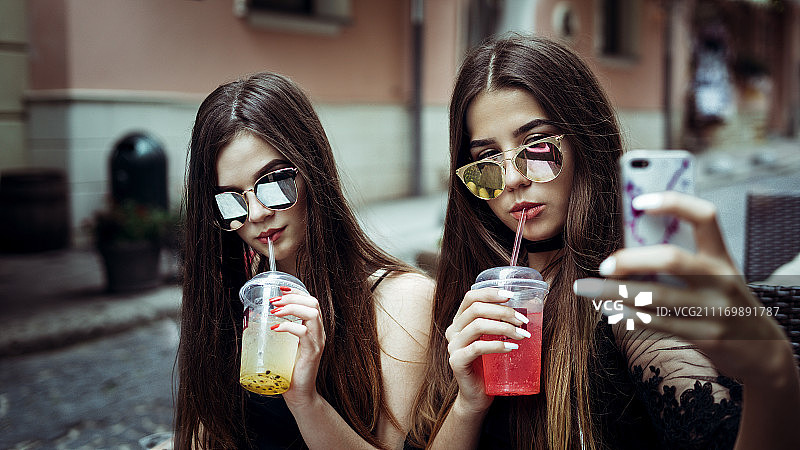 戴着太阳镜在城市街道上自拍的两名年轻女子图片素材