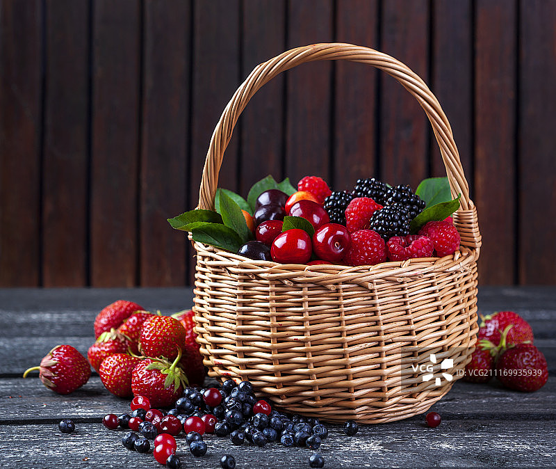 乡村木质背景中的篮装混合浆果图片素材