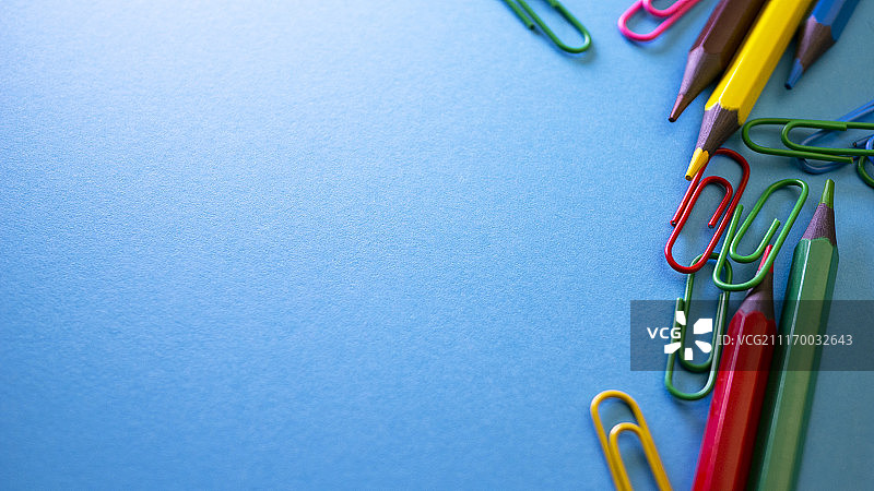 蓝色背景上的回形针和彩色铅笔图片素材