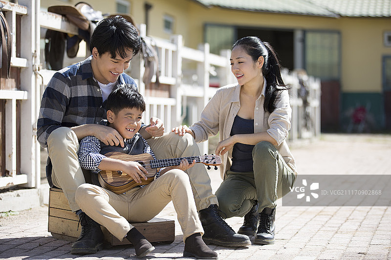 快乐一家人在马厩弹奏尤克里里琴图片素材
