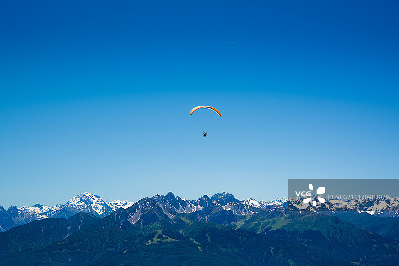 欧洲阿尔卑斯山脉上的黄色滑翔伞图片素材