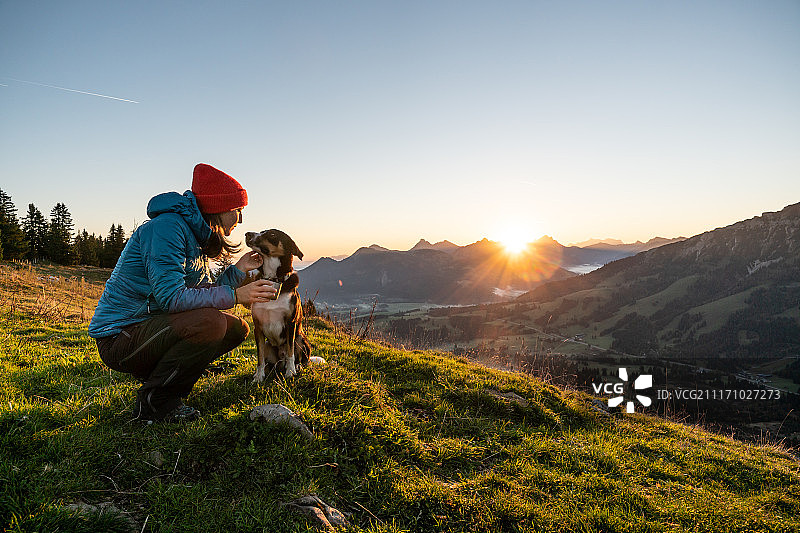 带狗在山上的女徒步旅行者图片素材