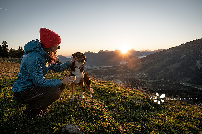 带狗在山上的女徒步旅行者图片素材