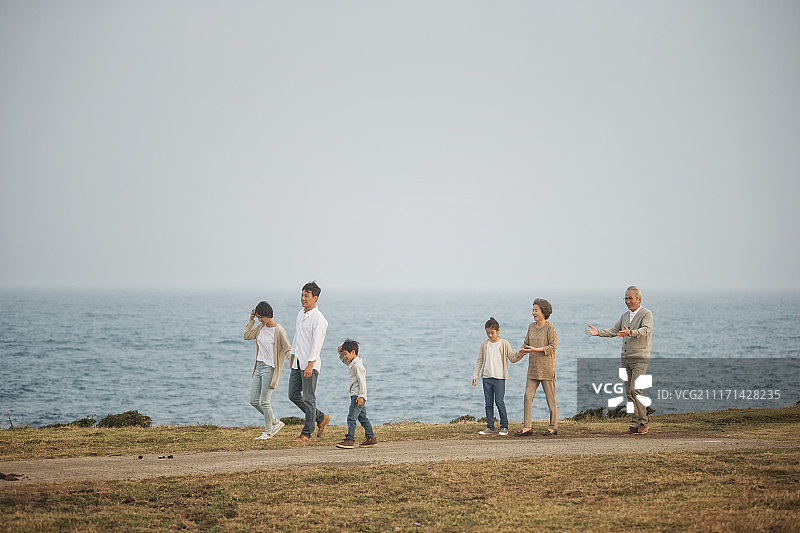 在济州岛山丘上大手牵小手行走的一家人摄影图片素材