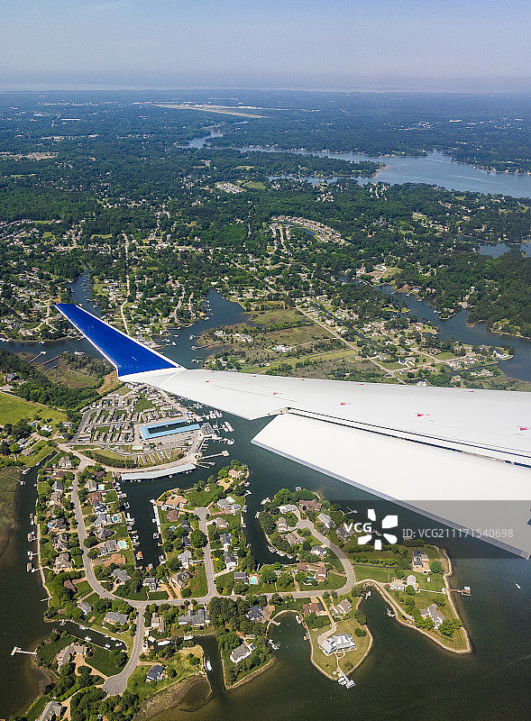 飞机飞越湖畔房屋的机翼，美国弗吉尼亚州波科森图片素材