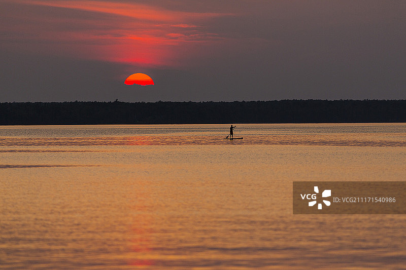 美国密歇根州：苏必利尔湖日落时划桨板的剪影远景图片素材