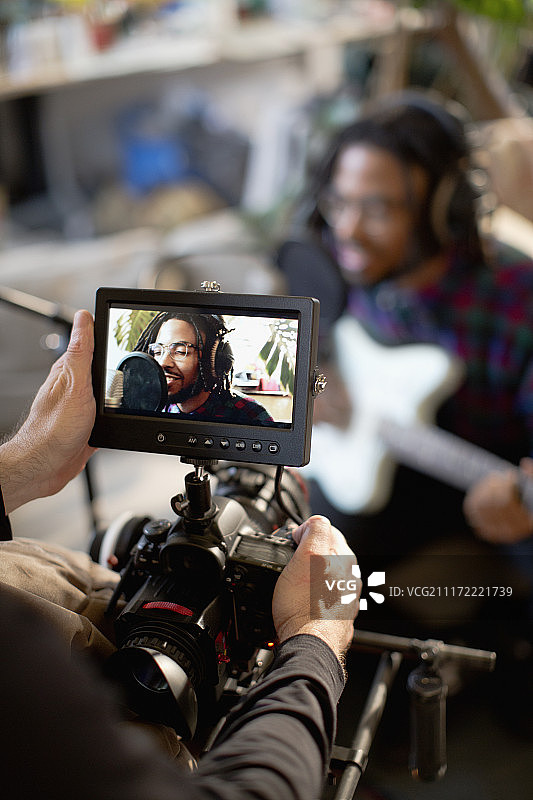 摄像师拍摄年轻男音乐家唱歌弹吉他图片素材