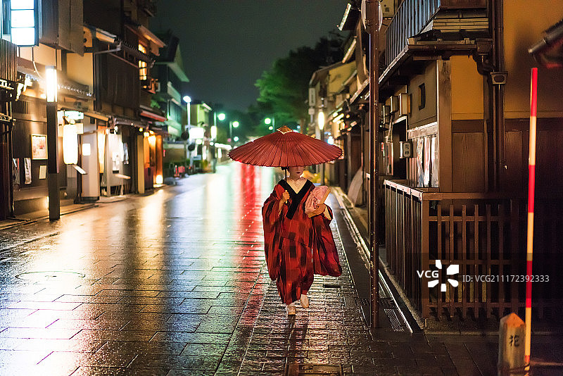 夜晚，一名穿着和服的日本艺伎走在京都的花见小路上图片素材