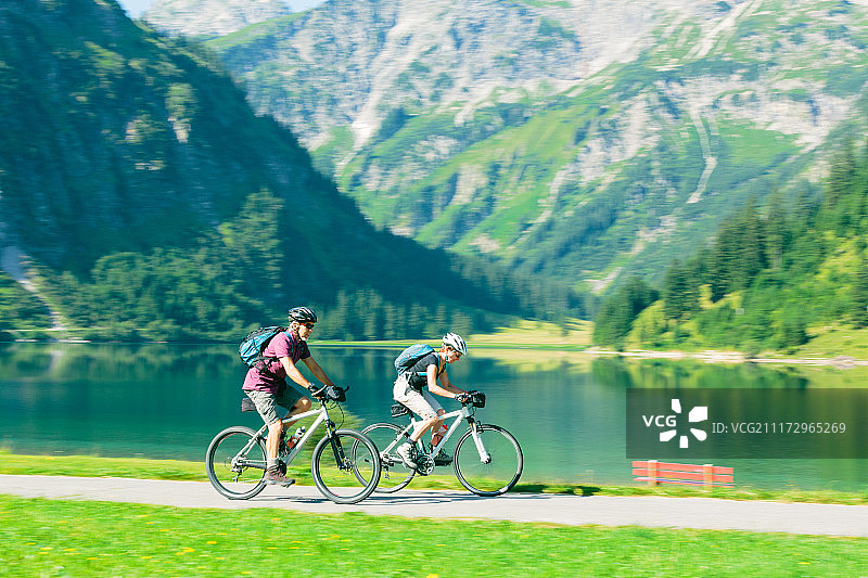 老年人在湖边骑行。图片素材