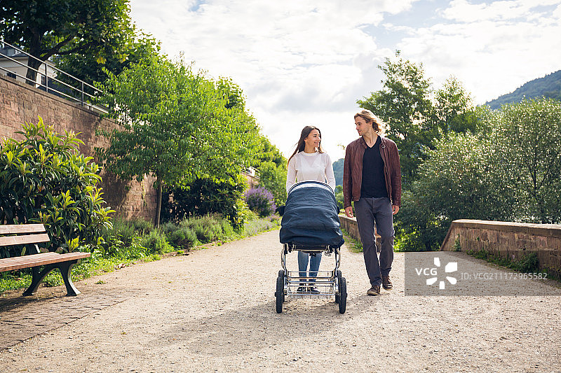 年轻父母在公园里推着婴儿车图片素材