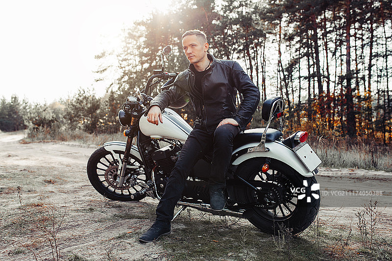 英俊的骑手在日落时骑着复古摩托车图片素材
