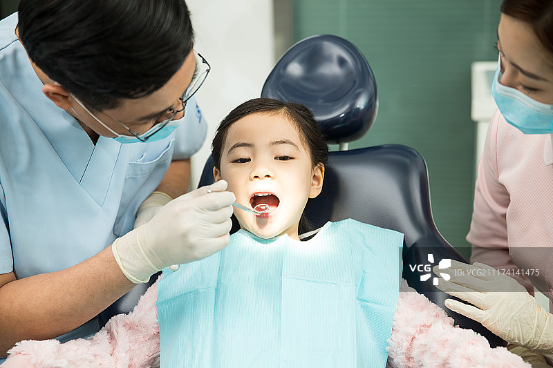 男牙医和女牙医助手在为小女孩检查牙齿图片素材