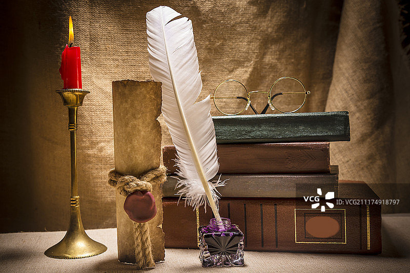 老式静物：书本、墨水台、羽毛笔和燃烧的蜡烛图片素材