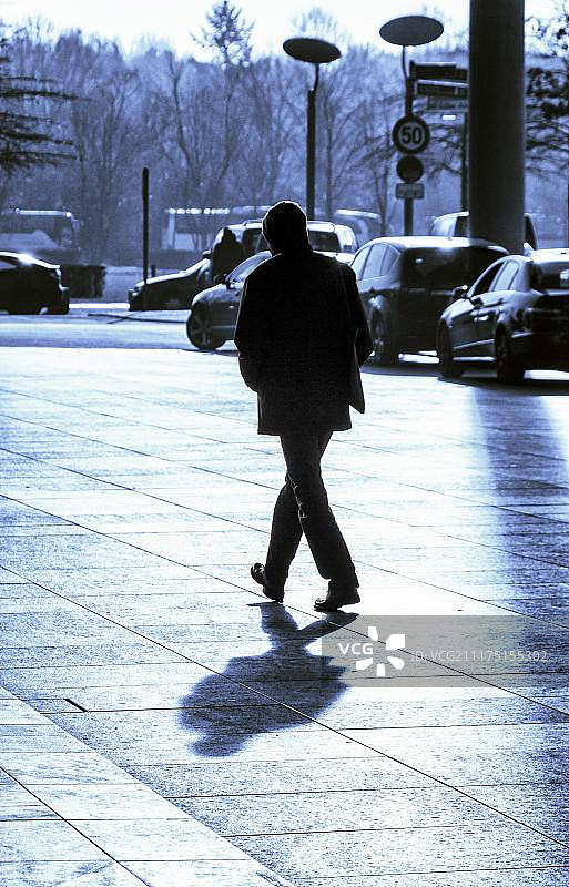 德国柏林，逆光下的过马路男子图片素材