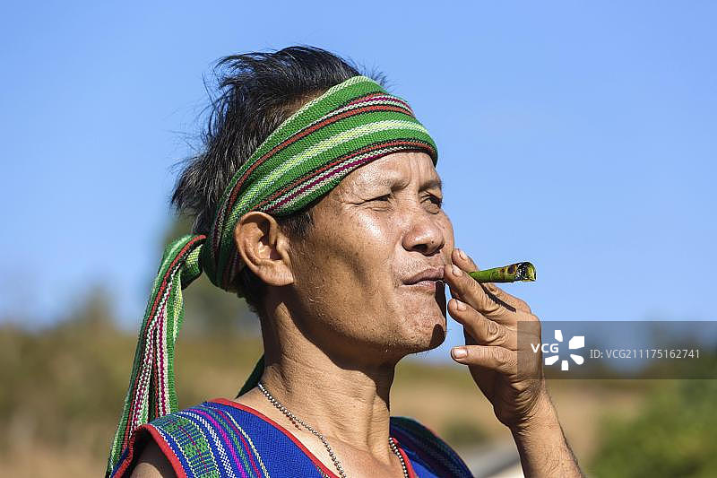 身穿传统服饰、吸着雪茄的男子，柬埔寨蒙多基里省普农族少数民族图片素材