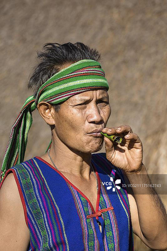 身穿传统服饰、吸着雪茄的男子，柬埔寨蒙多基里省普农族少数民族图片素材