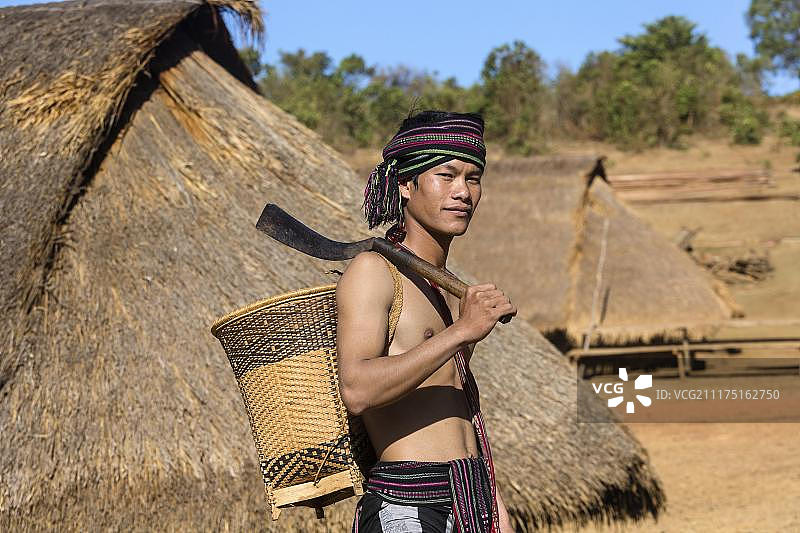 身穿传统服装的男子在柬埔寨蒙多基里省少数民族普侬族房屋前图片素材
