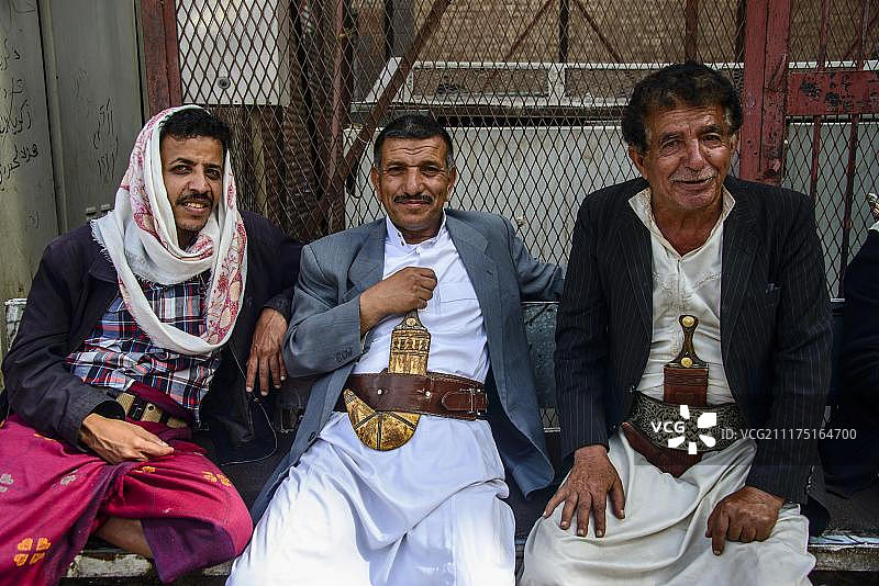 在也门萨那老城，男士们坐在房子前，带着他们的弯刀图片素材