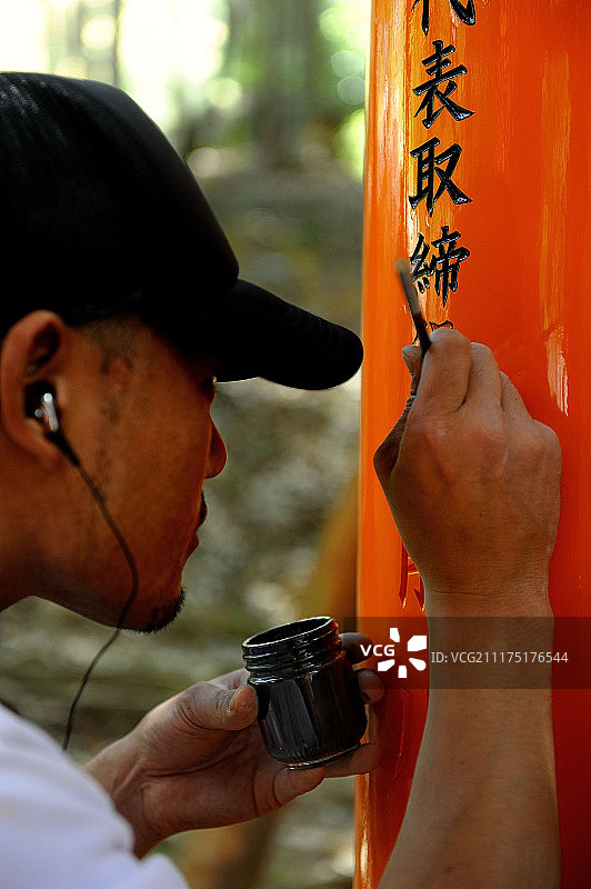 男子在伏见稻荷大社鸟居上书写捐赠者姓名图片素材