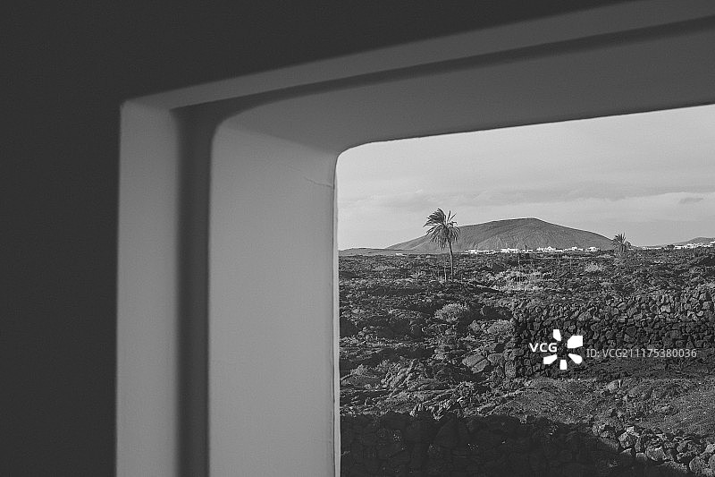 透过塞萨尔·曼里克基金会的窗户看到的火山和棕榈树，兰萨罗特岛，加那利群岛，西班牙图片素材
