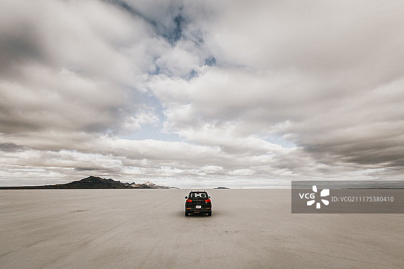 美国犹他州温多弗广阔荒凉盐滩上行驶的孤独汽车图片素材