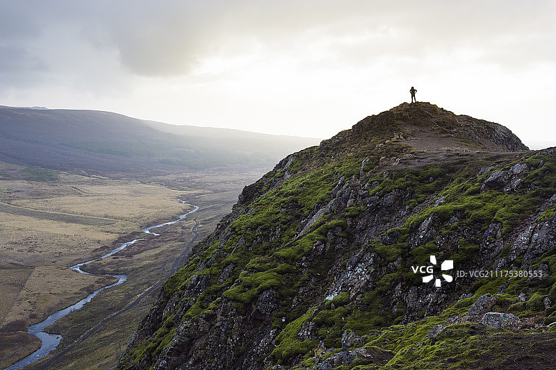 徒步旅行者站在长满苔藓的山顶，俯瞰冰岛盖锡尔河的剪影图片素材