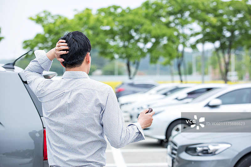 男人，一个人（人数），停车场，汽车（汽车类型），寻找（凝视），挠头（移动动作）图片素材