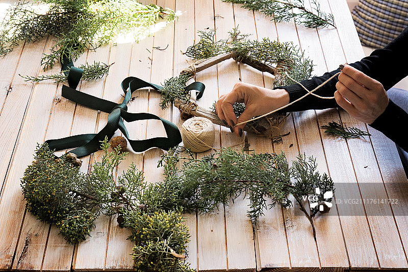 花店工作场景：制作圣诞红色木质花环图片素材