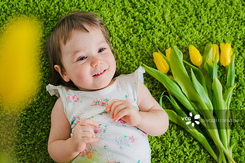 孩子躺在草地上，鲜花簇拥图片素材