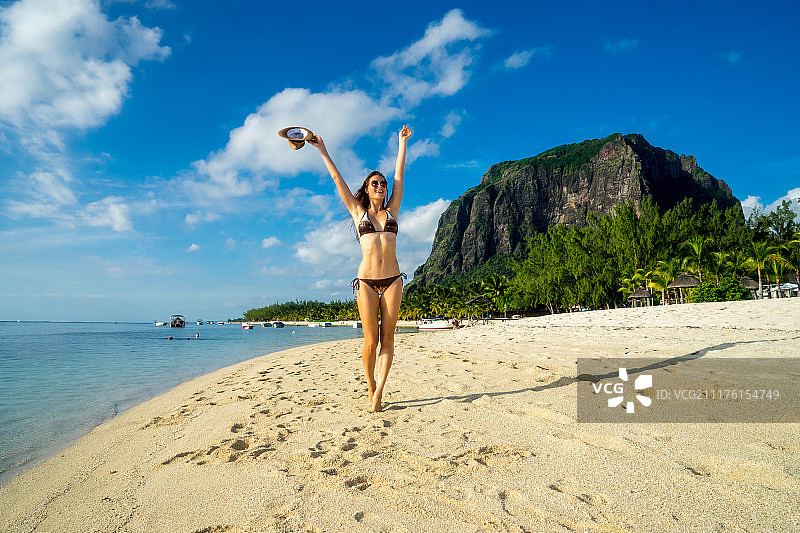 以风景如画的棕榈树、雪白的沙滩、海洋、船只为背景的女孩模特图片素材