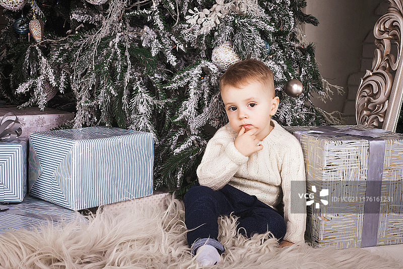 坐在室内圣诞树下的小男孩图片素材