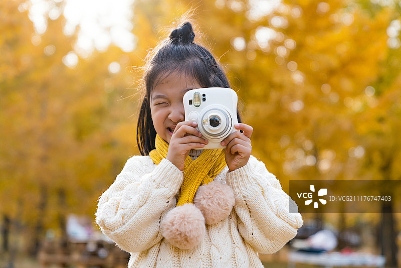 快乐的小女孩在银杏林手拿拍立得图片素材