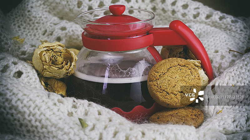 玻璃茶壶、燕麦饼干和白色针织披肩图片素材