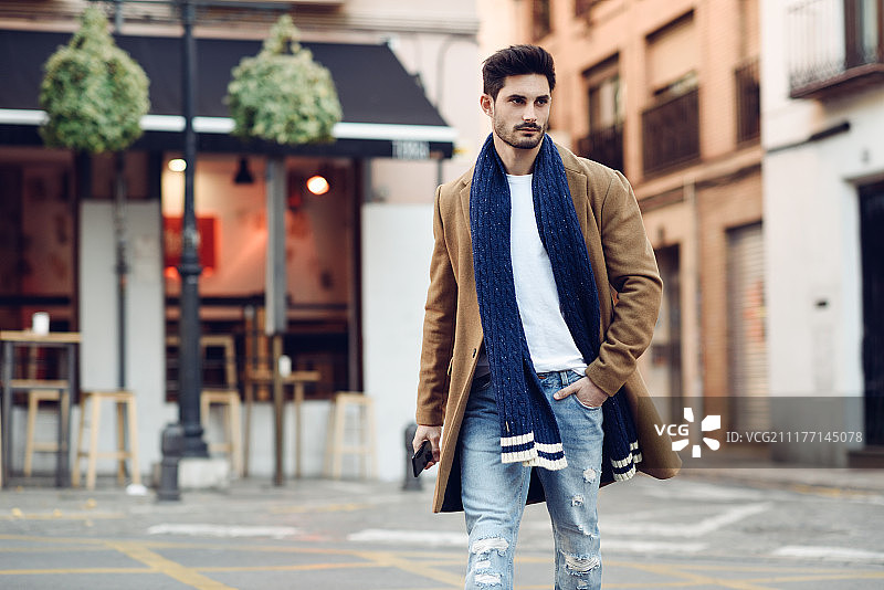 年轻男子身穿冬装，手拿智能手机图片素材