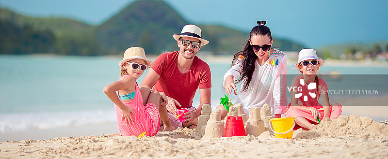 在热带海滩上堆沙堡的一家人图片素材