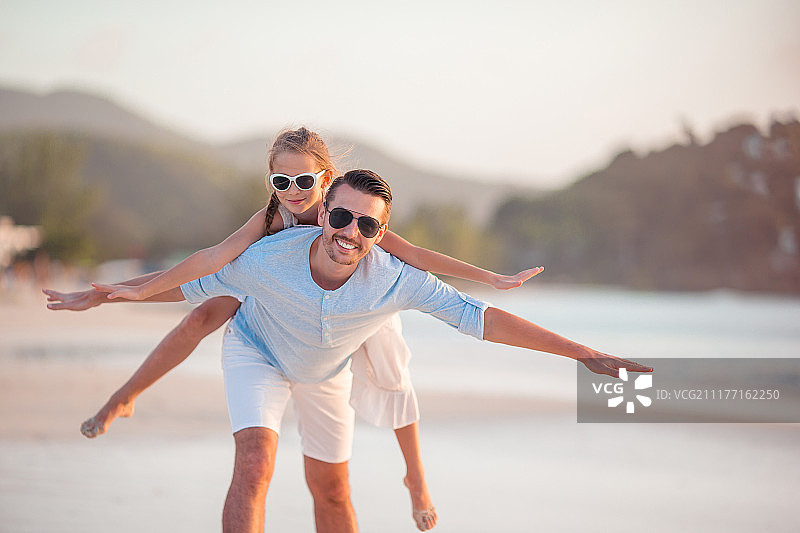 小女孩和快乐的爸爸在海滩度假时玩耍图片素材