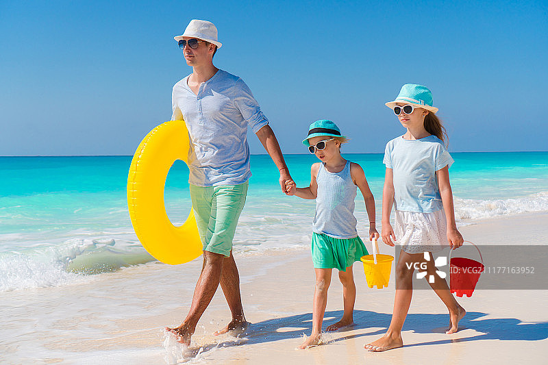 爸爸和孩子们在加勒比岛屿白色热带海滩上玩玩具图片素材