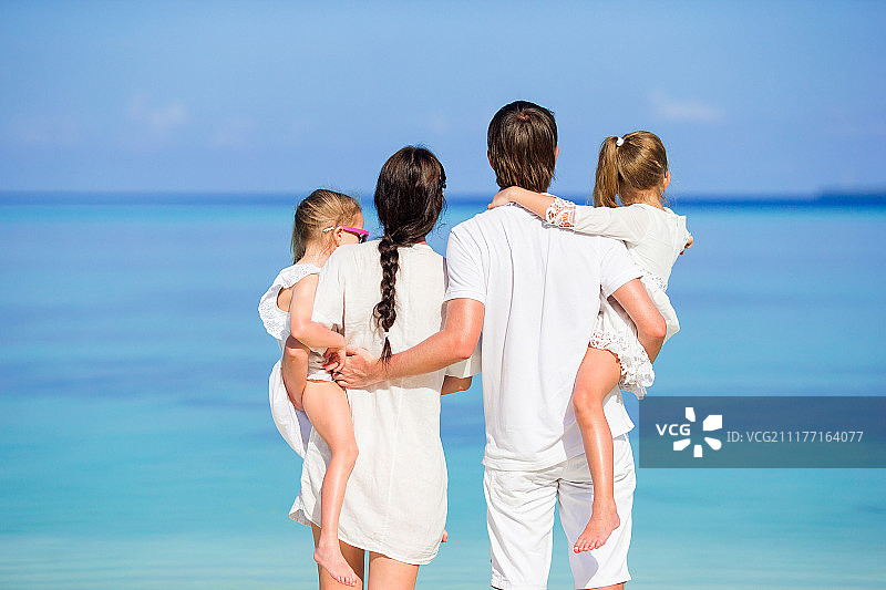 在海滩上快乐的白色家庭的背面图图片素材