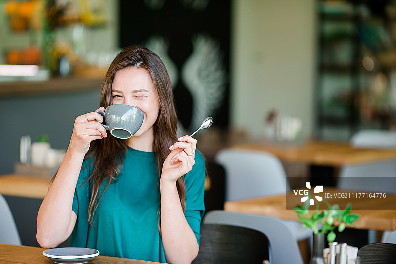 在户外咖啡馆享用美味咖啡的年轻快乐都市女性图片素材