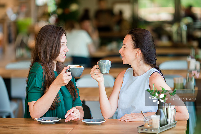 在户外咖啡馆喝咖啡的快乐年轻女性，交流与友谊的概念图片素材