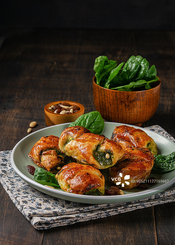 菠菜羊角包配葡萄干、松子和山羊奶酪，盘中有一碗菠菜图片素材