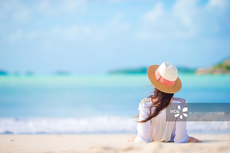 年轻女人享受阳光，在碧绿的海洋边日光浴图片素材