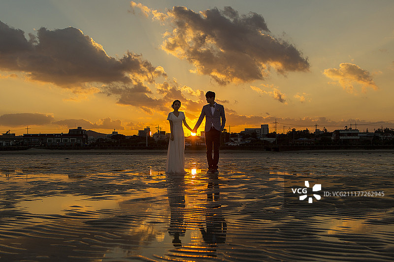 新婚夫妇在济州岛海滩日落时拍摄婚纱照图片素材