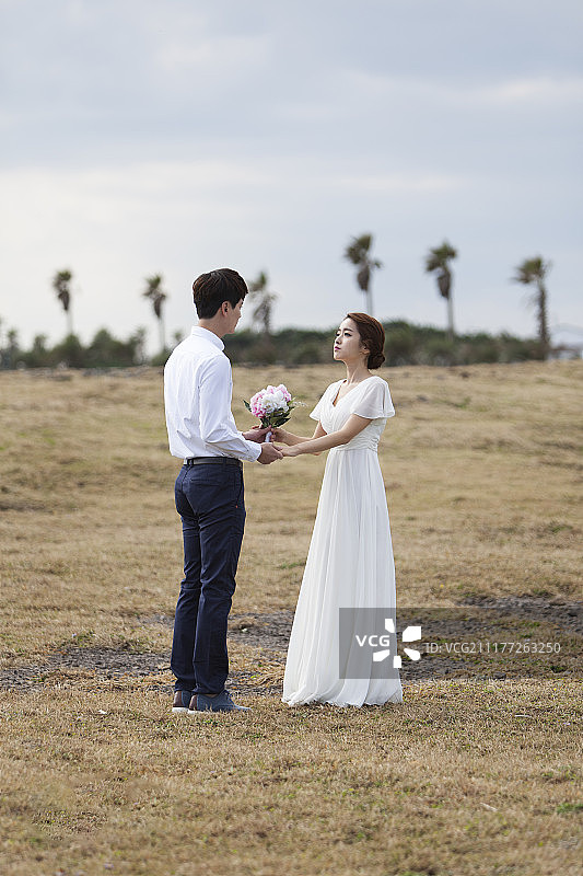 新婚夫妇手牵手面对面在户外的摄影图片素材