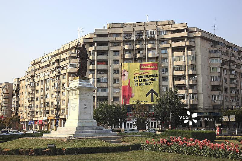 预制混凝土公寓楼，带有大型五金店广告海报，位于罗马尼亚普洛耶什蒂英雄广场图片素材