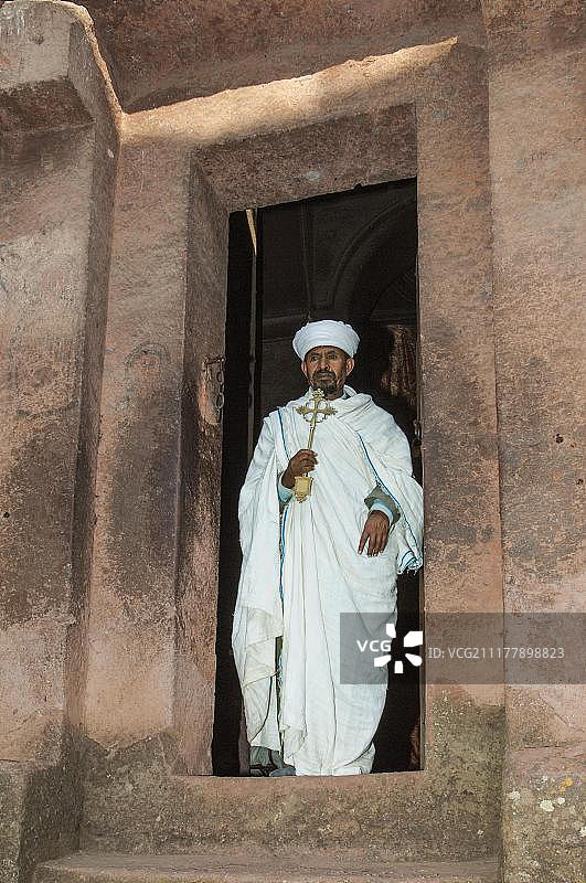 牧师在埃塞俄比亚拉利贝拉的 Bete Giyorgis 岩石教堂手持十字架图片素材