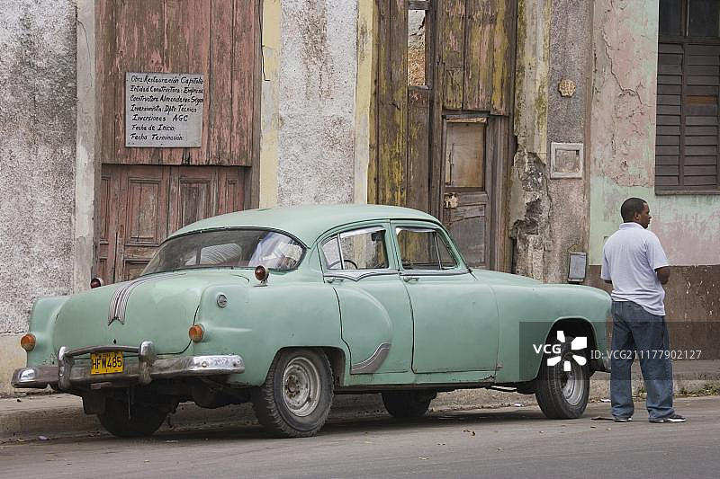古巴哈瓦那，中美洲，站在老爷车旁的当地男人图片素材