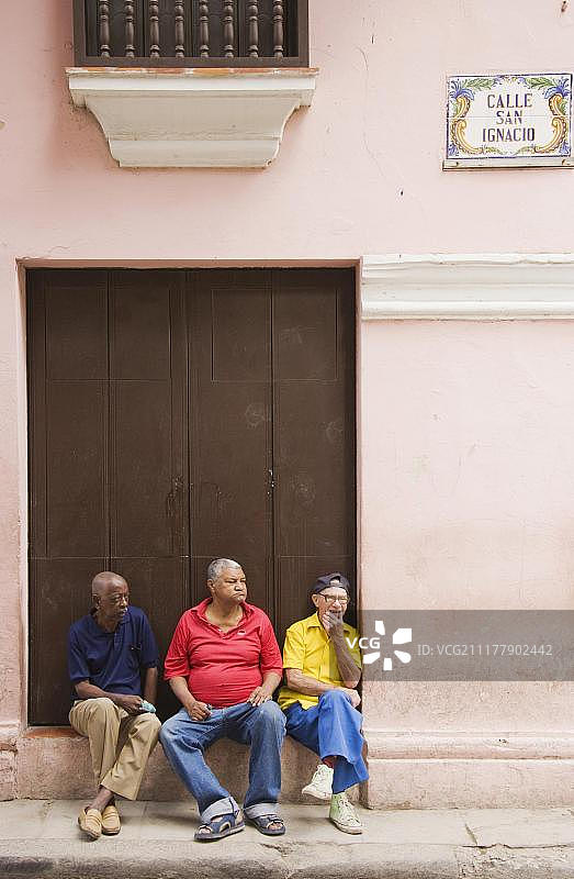 三位老人坐在建筑物前，古巴哈瓦那图片素材
