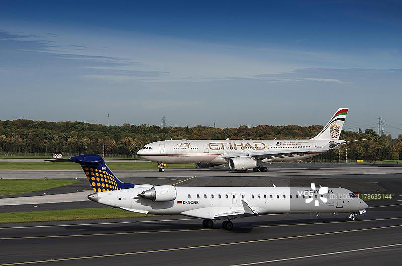 跑道上的两架飞机：欧洲之翼的庞巴迪CRJ900，以及阿提哈德航空的空客A330-343x，位于德国北莱茵-威斯特法伦州杜塞尔多夫国际机场图片素材