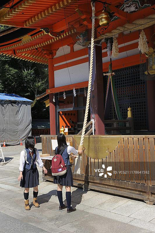 学生们穿着校服敲响神社上的钟,以吸引神灵的注意,八坂神社,圆山公园,日本,东亚,亚洲图片素材